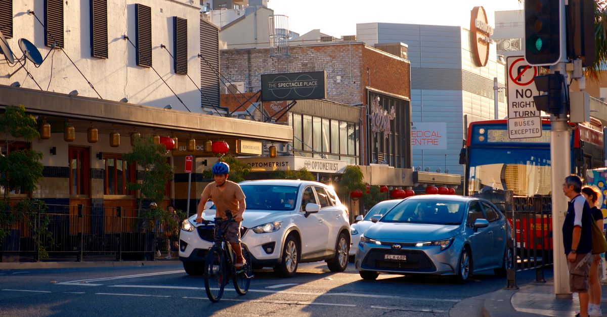 Busy city street scene featuring a cyclist in traffic during the daytime.